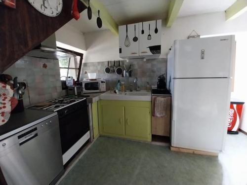 a kitchen with a white refrigerator and yellow cabinets at maison en pierres in Pradinas