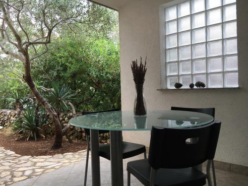 a glass table and chairs with a vase on it at Apartments Jakišnica in Jakišnica