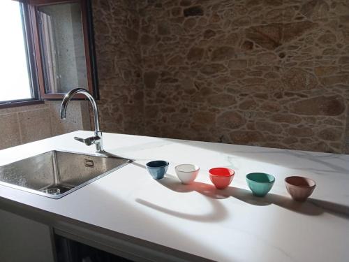 four bowls sitting on a counter next to a sink at Casa das Cazolas in Oia