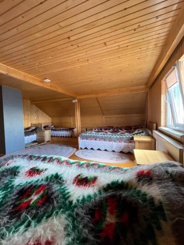 a room with two beds in a room with a wooden ceiling at Садиба Терентин in Rakhiv