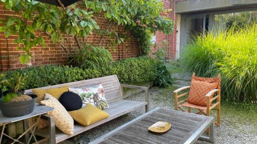 a patio with a bench and two chairs and a table at De Hamrokerij in Kortrijk