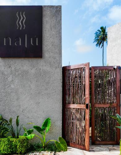 a sign on the side of a building with a gate at Natu Boutique Stays in São Miguel dos Milagres