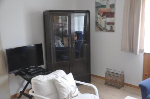 a living room with a tv and a chair at Ferienhaus Gansbach in Gansbach