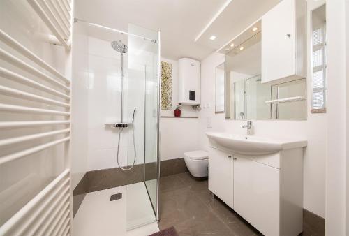 biała łazienka z prysznicem i umywalką w obiekcie Apartments Volf 1405 w mieście Peroj
