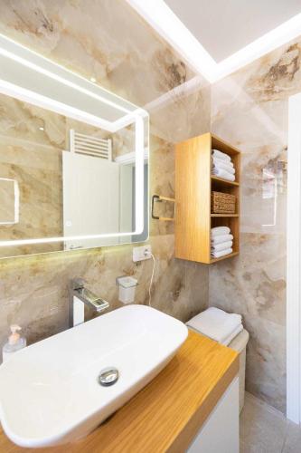 a bathroom with a white sink and a mirror at Zoto Luxury Apartment in Himare