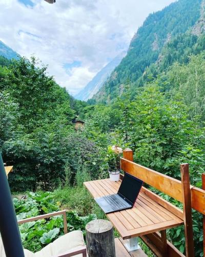 a laptop sitting on a wooden bench overlooking a mountain at Casa le Bouquetin in Introd