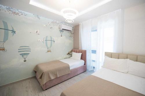 a bedroom with two beds and a wall with hot air balloons at Zoto Luxury Apartment in Himare
