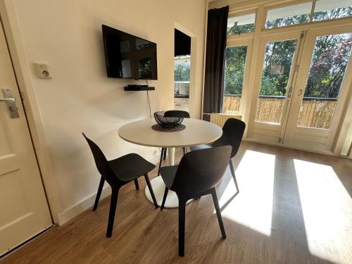 a dining room with a table and chairs and a television at Intimate independent apartment, Centre Dordrecht in Dordrecht