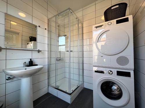 Un baño con lavadora y lavabo. en Intimate independent apartment, Centre Dordrecht, en Dordrecht