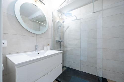 une salle de bain blanche avec un lavabo et un miroir dans l'établissement Confortable appartement - Cannes centre le Suquet, à Cannes