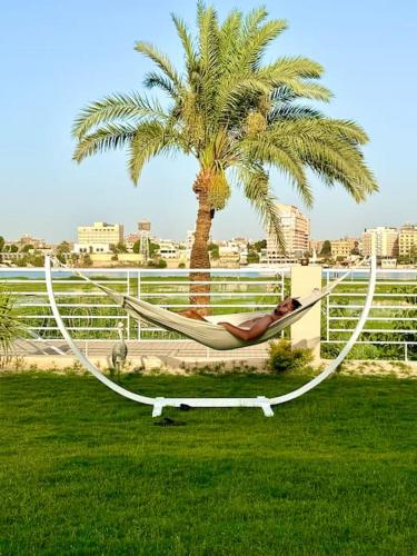 a woman laying in a hammock under a palm tree at Royal Nile Suites - Pool View 2 in Al Aqālitah