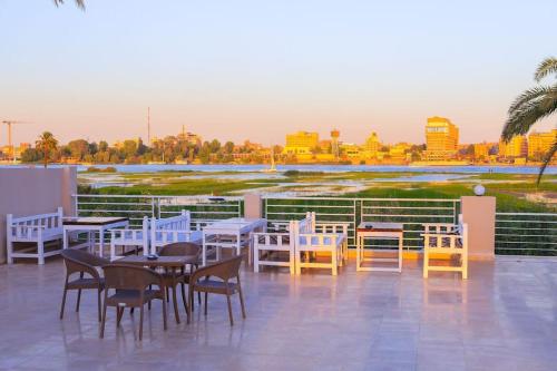 a patio with tables and chairs on a roof at Royal Nile Suites - Pool View 2 in Al Aqālitah