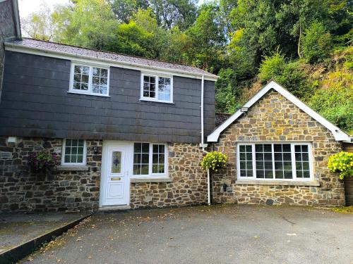 una casa in pietra con porta bianca e finestre di The Annex Roundaway Lodge a Okehampton