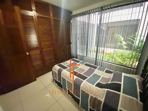 Cette chambre comprend un lit et une grande fenêtre. dans l'établissement Otro Yoses, à Los Yoses