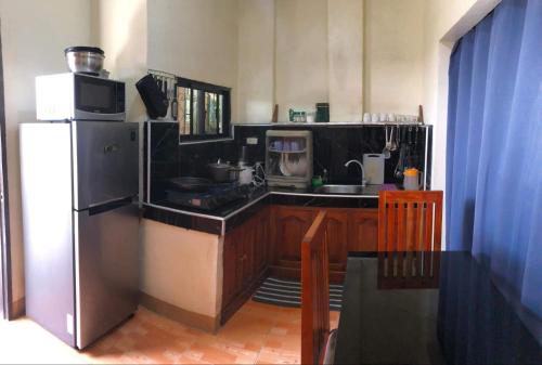 a kitchen with a refrigerator and a sink and a microwave at Fontelo Bungalow Guest House in Siquijor