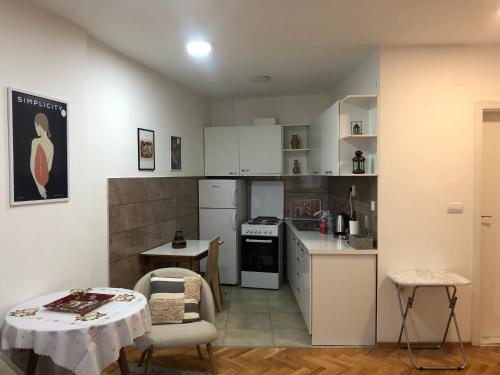 una cucina con mobili bianchi, tavolo e sedie di Snow white studio a Skopje