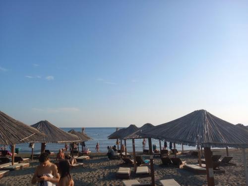 people sitting on the beach with umbrellas at Ulpiana - Apartments,Rooms,Hostel in Ulcinj