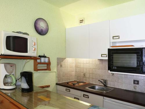 une cuisine avec un micro-ondes et un évier dans l'établissement Studio 4 pers. accès direct pistes, centre et balcon sud - FR-1-322-555, aux Orres