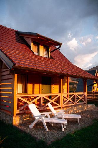a cabin with two white chairs and a house at Starry Sky Zlatibor in Krajevi