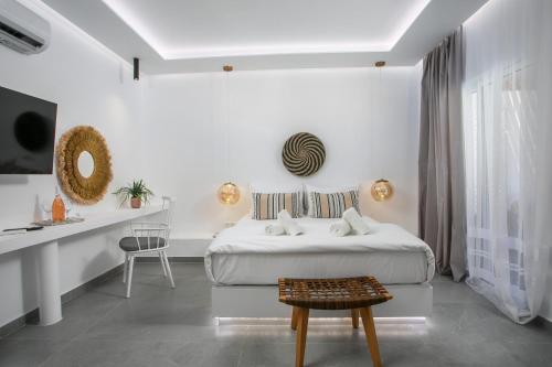 a white bedroom with a bed and a table at Calma Luxury Studios & Suites in Faliraki