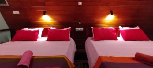 two beds with red pillows in a room at cinnamon avenue cabanas in Negombo