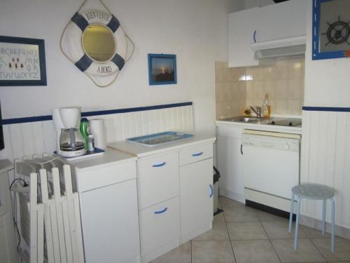 une petite cuisine avec des armoires blanches et un évier dans l'établissement Appartement rez-de-chaussée, au Barcarès