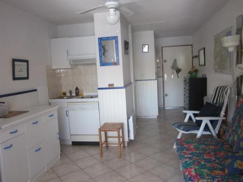 Il comprend une cuisine et un salon avec des placards blancs et un canapé. dans l'établissement Appartement rez-de-chaussée, au Barcarès