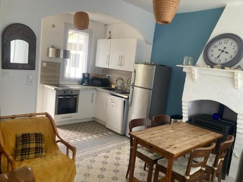 une cuisine avec une table et une horloge au mur dans l'établissement Maison de vacances bord de mer à Lion sur Mer, à Lion-sur-Mer