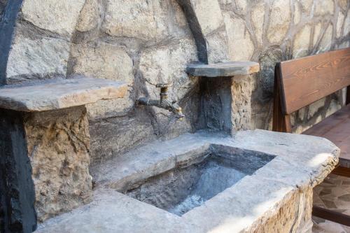 a stone sink in a stone wall with a water fountain at Къща за гости ANGELOVI in Veliko Tŭrnovo