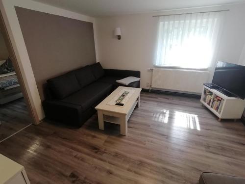 a living room with a black couch and a coffee table at Ferienwohnung in Mittelsaida in Großhartmannsdorf