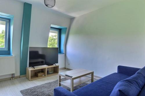 un salon avec un canapé bleu et une télévision dans l'établissement Appartement Charmant Très Proche Centre-Ville, Parking Gratuits, MULHOUSE CENTRE, à Mulhouse
