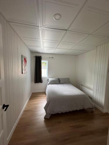 a bedroom with a bed in a white room at L'Escapade - magnifique appartement in Granby