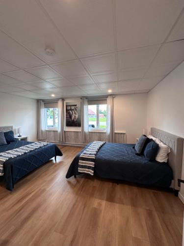 two beds in a large room with wooden floors at L'Escapade - magnifique appartement in Granby