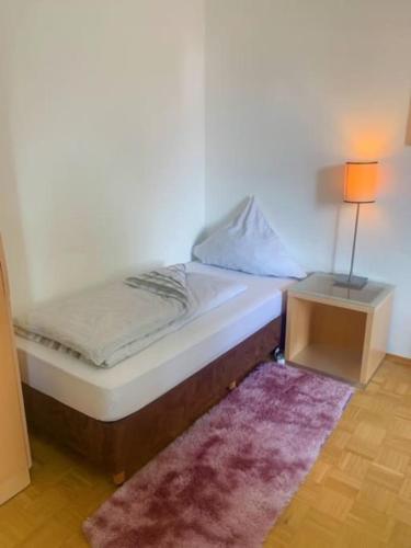 a bed in a room with a lamp and a rug at Ferienwohnung Dinh in Uhldingen-Mühlhofen