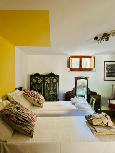 two beds in a room with yellow walls at Maison Le Calle in Vallo di Nera