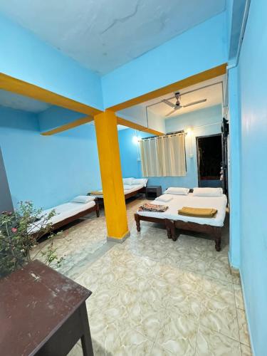 a room with two beds and a table and a mirror at Casanova by the Sea - Just a walk away to Canacona Beach in Palolem