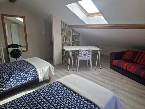 Cette chambre comprend deux lits, une table et un canapé. dans l'établissement La glycine, à Sinsat
