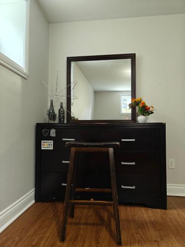 a black dresser with a mirror and a wooden stool at Cozy Basement rooms 2 bedroom 2 queen beds home stay in halifax Nova Scotia in Timberlea