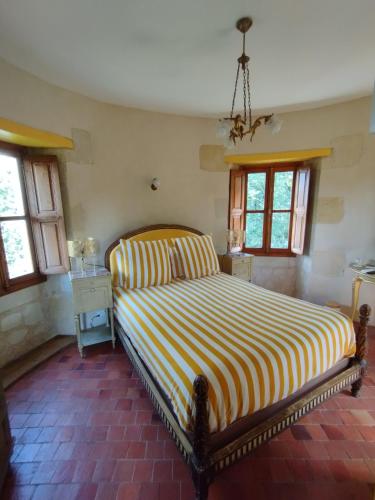 - une chambre avec un grand lit et un couvre-lit rayé dans l'établissement Chambres d'hôtes La Tour de Bellevue, à Saumur