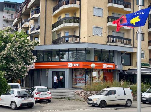 a building with cars parked in front of it at GJAKOVA - Cosy Apartment with 3,5 Bedrooms in the Best City Area in Gjakove