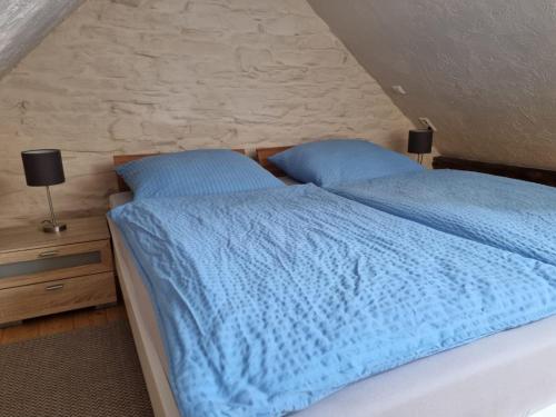 a bed with a blue comforter and two pillows at Ferienwohnung Fritzer in Ellenz-Poltersdorf