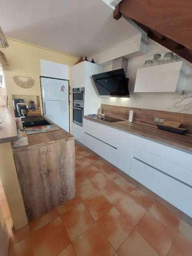 une cuisine avec des armoires blanches et un comptoir dans l'établissement Maison au bord de mer, à Sainte-Marie-Plage