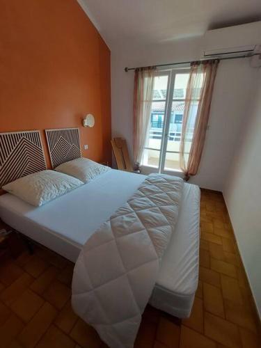 une chambre avec un grand lit blanc avec une fenêtre dans l'établissement Maison au bord de mer, à Sainte-Marie-Plage