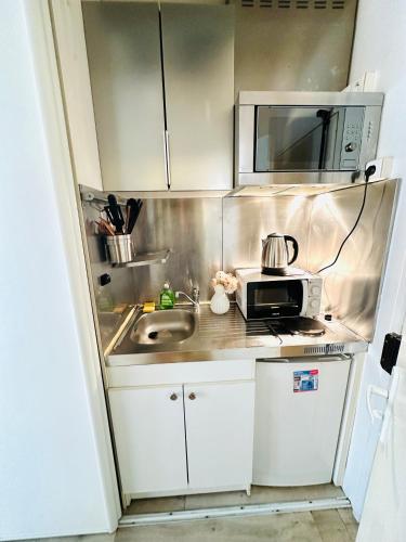 une petite cuisine avec un évier et un micro-ondes dans l'établissement Dream Dwell Paris - Cozy family studio near Quartier Marais IIIe Paris, à Paris