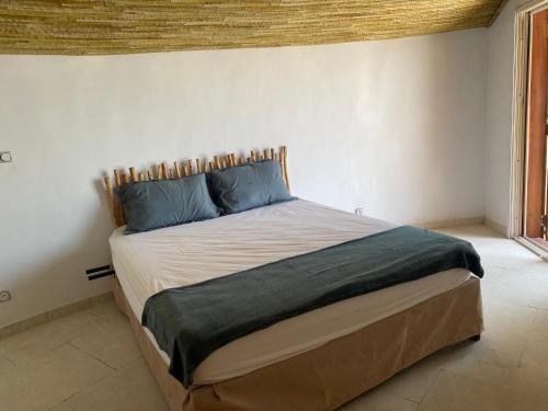 ein Schlafzimmer mit einem großen Bett mit blauen Kissen in der Unterkunft Villa pied dans l eau 5 chambres in Saly Portudal