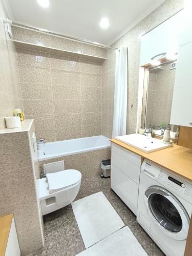 a bathroom with a toilet and a sink and a washing machine at Apart Lux Melestiu in Chişinău