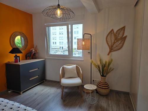 - une chambre avec une chaise, une commode et une fenêtre dans l'établissement La Belle Etape, à Sarreguemines