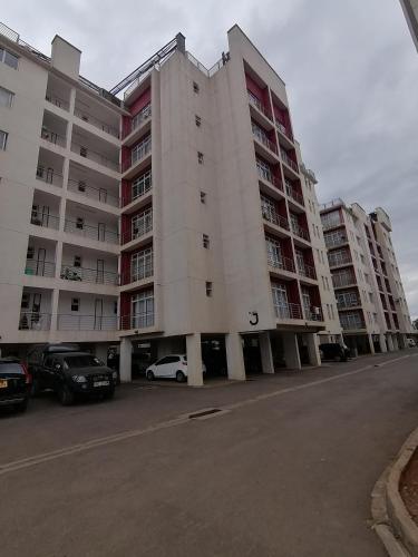 a large apartment building with cars parked in a parking lot at Classy Studio Apartment racecourse Gardens in Nairobi