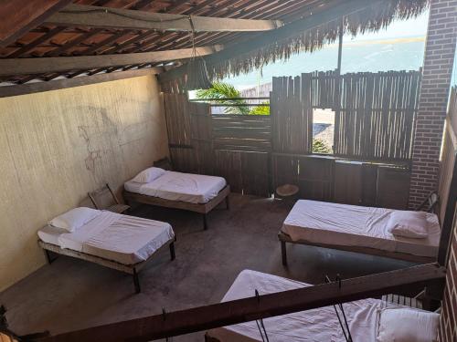 an attic room with three beds and a window at SOS Kite Hostel in Itarema