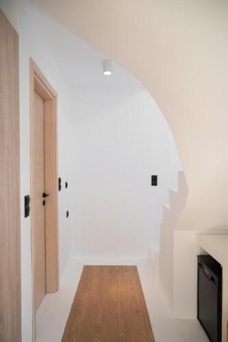 a white room with a wooden floor and a stairway at Evia Silence lighthouse in Boufalo